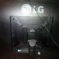 Back view of an LG monitor showing the stand mechanism and cable management with visible mounting hardware and adjustment joints