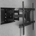 Two black TV wall mounts installed on a textured white wall, one extended outward and one folded flat against the wall