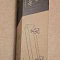 A cardboard box for a clamp-on cable management tray, showing product packaging with text and simple line drawings of the mounting hardware