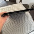 Person holding a black hair straightener above a gray and white chevron patterned placemat on a wooden dining table