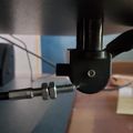 Close-up view of a mechanical device or tool with metal components, screws, and cables being operated by hand