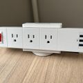 White power strip with multiple electrical outlets and USB ports on wooden surface