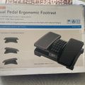 Package for a dual pedal ergonomic footrest with adjustable height settings and massage surface, shown on a gray chair