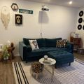 Modern living room with teal sectional sofa, vinyl records on wall, street sign decor, and striped area rug