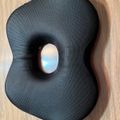 Black ergonomic seat cushion with center cutout on wooden floor