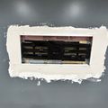 Electrical panel box recessed in wall with white painted frame around opening on gray wall