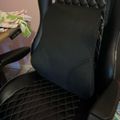 Black quilted gaming chair with lumbar support pillow in home office setting
