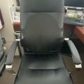 Black leather office chair with chrome armrests in a workspace setting