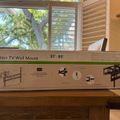 A boxed TV wall mount for 37-80 inch televisions sitting on a wooden surface near a window with blinds