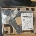 Unboxed TV wall mount kit with metal brackets, hardware, and instruction manual in cardboard packaging