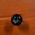 A circular black hole or opening in an orange textured wall or surface
