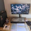 A computer workstation with a monitor displaying cherry blossoms, keyboard, mouse, papers, calculator, and a desktop computer tower on a wooden desk.