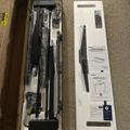 Unboxed desk or furniture assembly kit with metal parts, hardware, and instruction manual laid out on carpet
