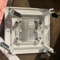 CPU cooler with metal heat sink and white mounting bracket with screws