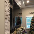 Modern living room with stone accent wall, wall-mounted TV, Christmas tree, and holiday decorations on mantel
