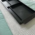 Black plastic drawer organizer tray with multiple compartments sitting on bubble wrap packaging material