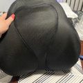 Person holding a dark gray mesh chair back or cushion on a striped surface