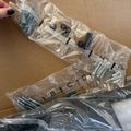 Hardware components and screws organized in clear plastic bags on cardboard surface