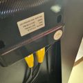 Back panel of an electronic device showing input ports with yellow connector cables plugged in and a product label