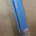 A blue packaged tilting TV wall mount in its retail box lying on a concrete floor