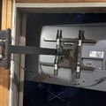 A TV wall mount bracket installed on a wall in what appears to be an unfinished room with wooden framing visible