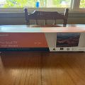 A boxed TV wall mount product sitting on a wooden table near a window