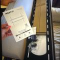 Person holding instruction manual for MOUNT-IT TV wall mount with opened product box containing mounting hardware and components