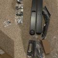 Disassembled furniture parts and hardware components laid out on carpet, including metal rails, brackets, and small bagged hardware pieces