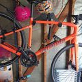 Orange Specialized bicycle hanging on wooden wall rack in garage storage area