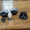 Several black guitar picks of different shapes and sizes arranged on a wooden table surface