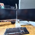 Dual monitor computer setup on wooden desk with black keyboard and desk lamp