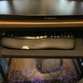 A computer desk setup with a monitor, keyboard with wrist rest, and mouse on a pull-out keyboard tray