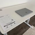 White desk with gray laptop and assembly instructions for furniture