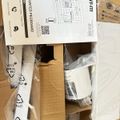 An unboxed desk-mounted pegboard organizer with instruction manual and plastic components laid out on cardboard packaging