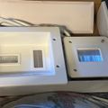 Two white electronic devices with cables and blue LED display, one appears to be a control unit or testing equipment