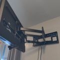 A large flat-screen TV mounted on an articulating wall bracket that allows it to swivel and extend from the wall in a corner room setting