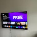 Wall-mounted Vizio TV displaying streaming service menu with various app icons and free content options