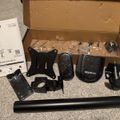 Unboxed monitor desk mount kit with instruction manual, mounting hardware, clamps, and adjustment arm components laid out on carpet