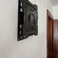 A black TV wall mount bracket attached to a white wall in a room with wooden door trim