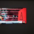 A computer screen or monitor displaying a cybersecurity warning message with binary code and red alert graphics about computer vulnerabilities and hacking threats