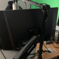 A desk setup with a computer monitor, microphone on an adjustable boom arm, and green screen backdrop for recording or streaming
