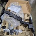 Unboxed equipment with black metal components and plastic wrapped parts in cardboard packaging