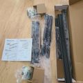 Unassembled furniture parts and hardware laid out on wooden floor with instruction manual