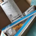 An opened product box containing a wall-mounted TV cable concealer kit with installation instructions and hardware components visible inside