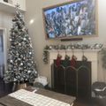A festively decorated living room with a Christmas tree, fireplace with stockings, and holiday garland during the Christmas season