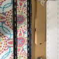 Unboxed items on a colorful patterned surface including a black frame or case and cardboard packaging materials
