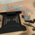 Disassembled laptop stand components and hardware parts laid out on a wooden desk surface