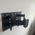 Black articulating TV wall mount bracket installed on white wall