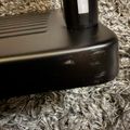 Black electronic device base sitting on gray shag carpet