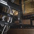 Black metal staircase with handrails in an indoor space with wooden structural elements visible in the background
